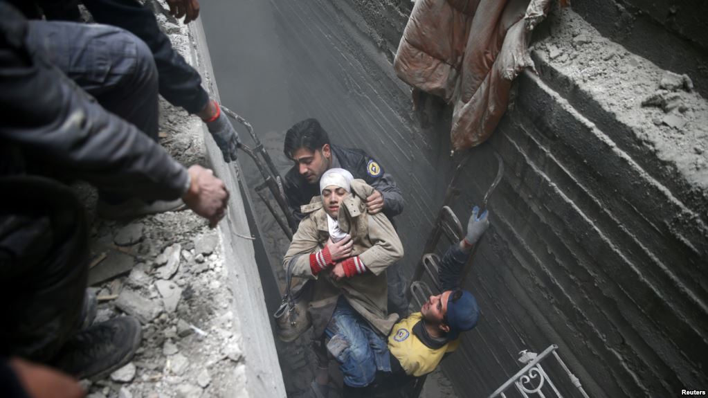 Syria Civil Defense members help an unconscious woman from a shelter in the besieged town of Douma, Eastern Ghouta, Damascus, Syria, Feb. 22, 2018. Syrians in Ghouta Tweet for Their Lives as Bombs Rain Down “For God’s sake help us!” reads a message on Twitter attached to a video showing two small girls, bleeding and crying in a smoky, chaotic house. It is part of a social media campaign surrounding the crisis in Ghouta, Syria, where more than 400 civilians have been killed in the past six days, according