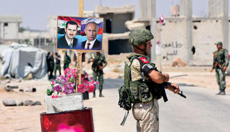 عناصر من الشرطة الروسية قرب صورتين لبوتين والاسد في غوطة دمشق