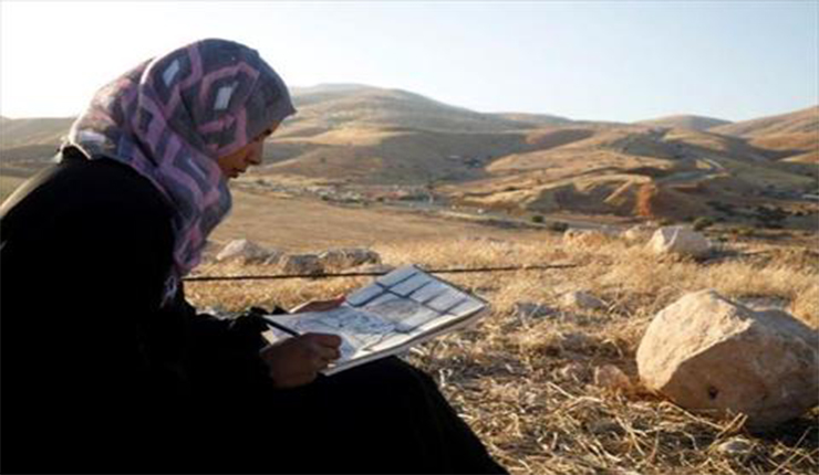 الرسامة الفلسطينية خديجة بشارات ترسم في غور الأردن بالضفة الغربية (رويترز)