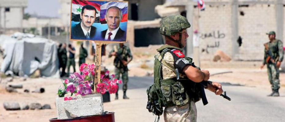 عناصر من الشرطة الروسية قرب صورتين لبوتين والاسد في غوطة دمشق 